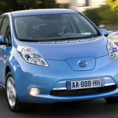 Un coche azul Nissan Leaf, uno de los coches mas fiables de segunda mano, circula por una carretera.