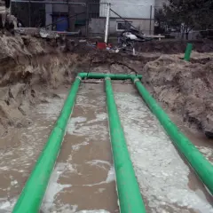 Instalacja gruntowego wymiennika ciepła w wykopie z zielonymi rurami.