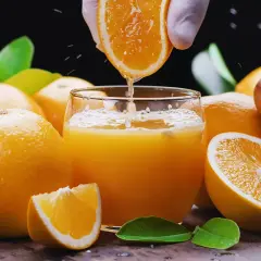 Un vaso de zumo de naranja recién exprimido, rodeado de naranjas frescas. ¡Cuidado! el zumo de naranja engorda si se abusa de él.