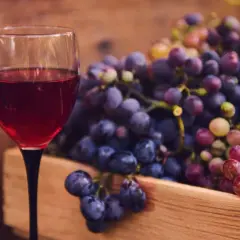 Kieliszek czerwonego wina i skrzynka winogron. Idealne składniki, by dowiedzieć się, jak zrobić wino wytrawne czerwone.