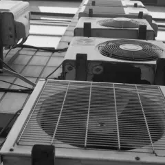 Vue en contre-plongée de plusieurs unités de climatisation extérieures, dont une pompe à chaleur triphasé, alignées sur un mur.