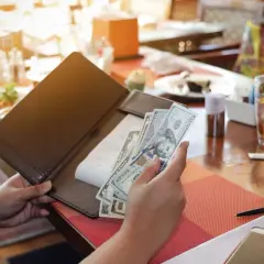 Rachunek w restauracji, ręka trzyma banknoty dolarowe. Poproszę rachunek po angielsku.
