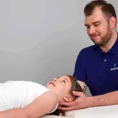 Terapia czaszkowo-krzyżowa pomaga dziecku z depresją. Terapeuta delikatnie dotyka głowy dziewczynki.
