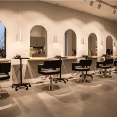 Estilo moderno en peluquería. Sillones negros, espejos arqueados y plantas. Descubre los secretos de agua peluquería para un look radiante.