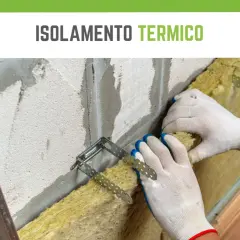 Mani guantate installano materiale isolante termico in lana di roccia su una parete grezza, fissato con staffe metalliche.