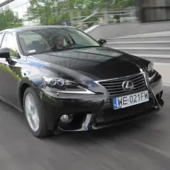 Czarny Lexus IS, doskonały wybór wśród lexusów używanych, pędzi ulicą. Kierowca wpatrzony w drogę.