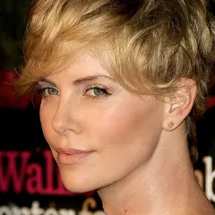 Charlize Theron w fryzurze pixie, która dodaje objętości cienkim włosom, z subtelnym makijażem i złotą biżuterią.