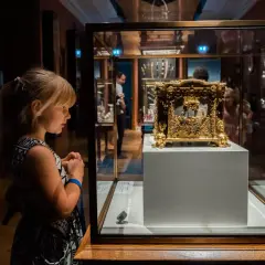 Dziewczynka z zaciekawieniem ogląda złoty, zabytkowy przedmiot w gablocie w muzeum Czartoryskich.