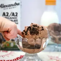 Dziecko palcem dotyka pysznych lodów z mleka krowiego, posypanych czekoladowymi wiórkami.