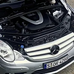 Motor de Mercedes Clase R, con capó abierto. Se aprecian componentes mecánicos y el logo de Mercedes. Posibles mercedes clase r problemas.