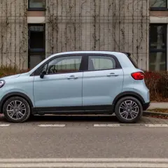 Jasnoniebieski Leapmotor T03 zaparkowany przy nowoczesnym budynku z pnączami.