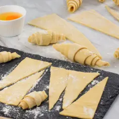 Ingredientes para la receta de cruasanes: masa enrollada, huevos batidos y cáscaras de huevo.