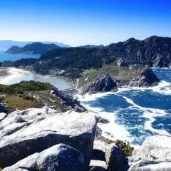 Paisaje costero con rocas, mar azul y una playa de arena blanca. Así es donde está Galicia, un paraíso natural.