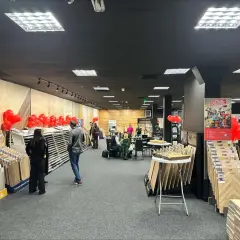 Wnętrze salonu z wystawionymi panelami podłogowymi, dekoracjami z balonów i ludźmi.