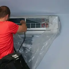 Un technicien effectue l'entretien d'une climatisation murale, une tâche essentielle pour tout locataire ou propriétaire soucieux de son confort.