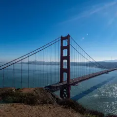 Ikoniczny most w San Francisco rozciąga się nad błękitną wodą, z miastem w oddali.
