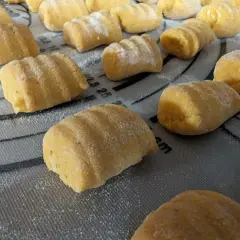 Gnocchi de patate douce faits maison, prêts à être cuits, saupoudrés de farine sur une planche.
