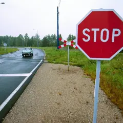 Znak stop przy przejeździe kolejowym. Kierowca powinien uważać, by nie dostać mandatu za niezatrzymanie się.