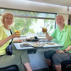 Ett par skålar med öl på ett tåg till München. De njuter av en måltid med bröd, ost och charkuterier medan landskapet susar förbi utanför fönstret.