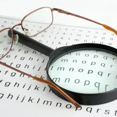 Okulary i lupa na tablicy Snellena. Badanie wzroku zajęło półtorej godziny.