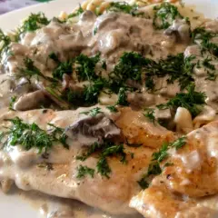 Kurczak z mascarpone i grzybami w kremowym sosie, podany z makaronem i posypany świeżym koperkiem.