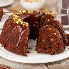 Pyszna babka na oleju, polana czekoladą i posypana pistacjami, czeka na kawę.