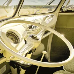 Wnętrze klasycznego VW T1. Biała kierownica, deska rozdzielcza i zielona tapicerka.