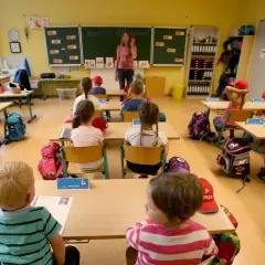 Ein helles Klassenzimmer, bereit für den Unterricht. Kinder sitzen an ihren Tischen, Rucksäcke und Lernmaterialien sind schon da. Das Klassenzimmer einrichten ist abgeschlossen.