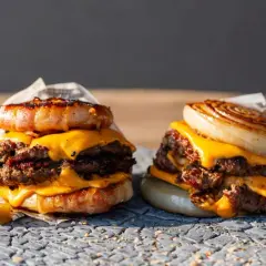 Zwei saftige "Flying Dutchman Burger" mit doppelt Fleisch, geschmolzenem Käse und einer Zwiebel- bzw. Speckkrone.