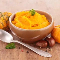 Aksamitne puree z dyni w glinianej misce, obok małe dynie, kasztany i łyżka. Idealne na jesienne dni.