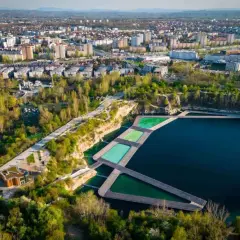 Widok na zalew Zakrzówek w Krakowie z drewnianymi pomostami i basenami. W tle rozciąga się miejska zabudowa.