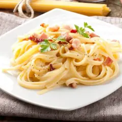 Spaghetti carbonara - przepis oryginalny ze śmietaną. Kremowy sos, chrupiący boczek i świeża natka pietruszki na talerzu. Pyszne danie gotowe w kilka minut.