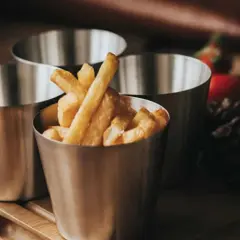 Tre metallbägare med hemmagjorda pommes frites. En bägare är fylld med gyllene pommes.