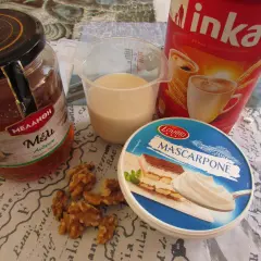 Składniki na kawę Inka z mlekiem: słoik miodu, kubek mleka, opakowanie serka mascarpone, orzechy włoskie i puszka kawy Inka.
