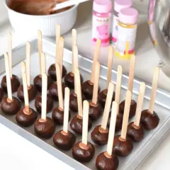 Chokladbollar på pinnar, redo att dekoreras. En bricka full med dessa goda cake pops väntar på att bli klädda i glasyr och strössel.