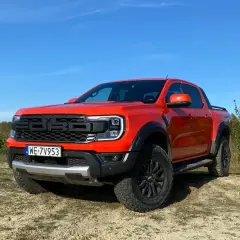 Pomarańczowy Ford Raptor na tle nieba i lasu. Zastanawiasz się nad jego **spalaniem**?
