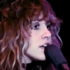 Stevie Nicks śpiewa "Dreams" Fleetwood Mac, jej charakterystyczne falujące włosy i intensywne spojrzenie.
