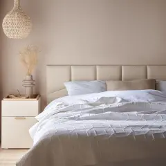 Miękkie, tapicerowane panele tworzą elegancki **pomysł na zagłówek do łóżka**. Jasna kolorystyka i minimalistyczny design.