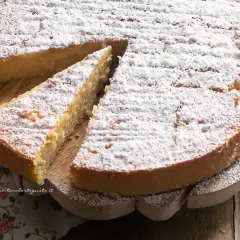 Deliziosa torta con farina di riso, cosparsa di zucchero a velo, servita su un tagliere di legno.