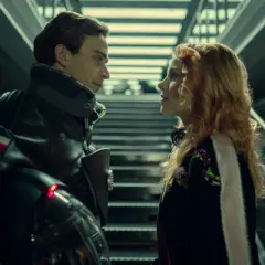 Dziewczyna patrzy na kosmonautę w futurystycznym skafandrze.