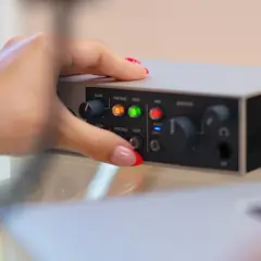 Dłoń z paznokciami ustawia pokrętło na interfejsie audio. Dowiedz się, jak podłączyć mio smartbox iii.