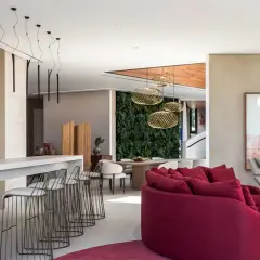 Elegante sala con barra y taburetes, una pared verde y una lámpara quinqué techo que ilumina el espacio.