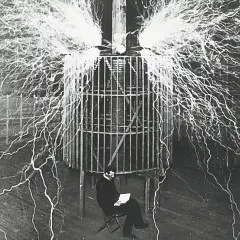 Nikola Tesla w klatce, otoczony wyładowaniami elektrycznymi, badał, kto wynalazł prąd.