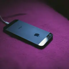 iPhone podłączony do ładowania. Dowiedz się, jak zmierzyć pojemność baterii, aby wiedzieć, jak długo telefon będzie działał.