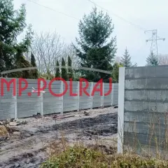 Gotowy fundament pod ogrodzenie, czekający na pozwolenie. W tle drzewa i linia energetyczna.