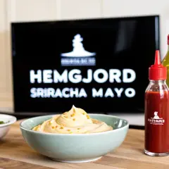 En skål med krämig sriracha mayo med topping, bredvid en flaska sriracha och en grön sås. Perfekt för ditt sriracha mayo recept!