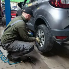 Mechanik wymienia koło w samochodzie. Czy w Polsce obowiązują opony zimowe? To pytanie zadaje sobie wielu kierowców przed sezonem.