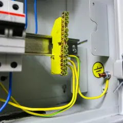 Instalacja elektryczna z wyłącznikami i listwą zaciskową. Pokazuje, jak zrobić uziemienie szpilkowe, łącząc przewody z listwą i obudową.