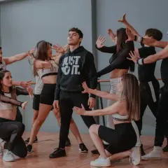 Un gruppo di giovani ballerini in abiti sportivi esegue una coreografia di danza pop in uno studio.