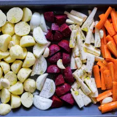 Ugnsrostade rotfrukter: potatis, morötter, palsternacka, rödbetor och lök, kryddade och redo för ugnen.